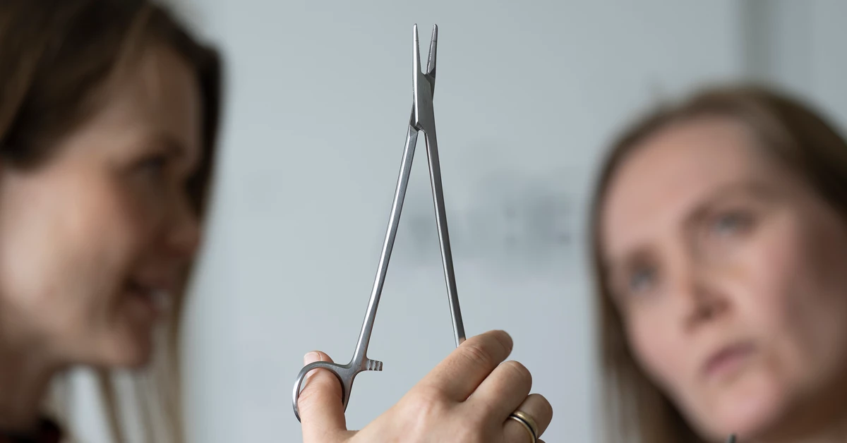 Maria Gaden, uddannet jordemoder og tidligere leder af Center for Bæredygtige Hospitaler, holder et flergangsinstrument op.